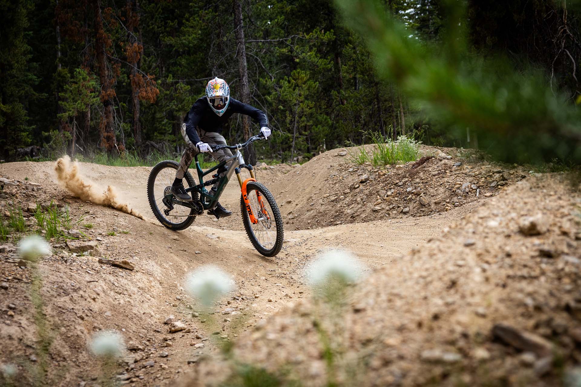 Mountain biker riding a trail, kicking up dirt. Exploring the world of RKT Optics.