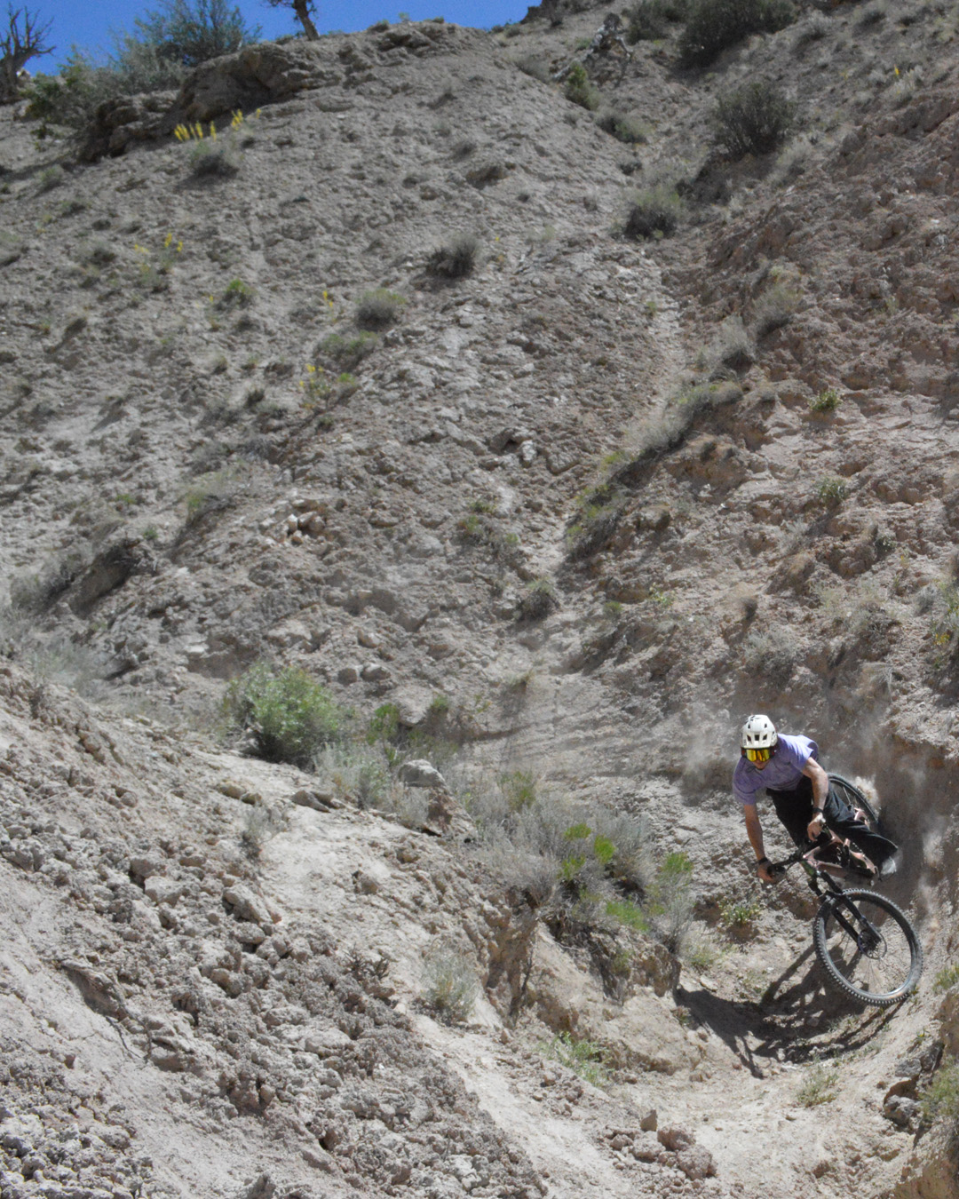 Mountain biker mid-air on a downhill bike jump, showcasing bike's orange suspension.